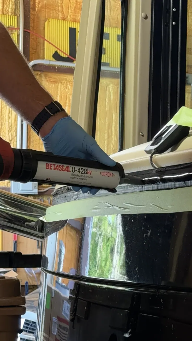 Gloved hand using an applicator along a motorhome windshield area
