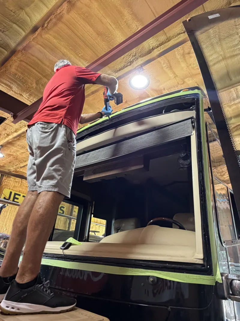 Technician working along the top of a motorhome windshield opening